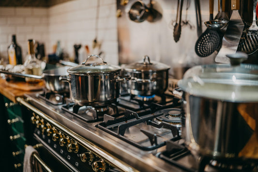 Close-up of a gas range with multiple pots cooking, showcasing powerful burners and high-performance kitchen appliances.