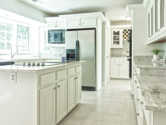 Bright, modern Canadian kitchen with stainless steel refrigerator, white cabinetry, and granite countertops showcasing popular kitchen appliance trends.