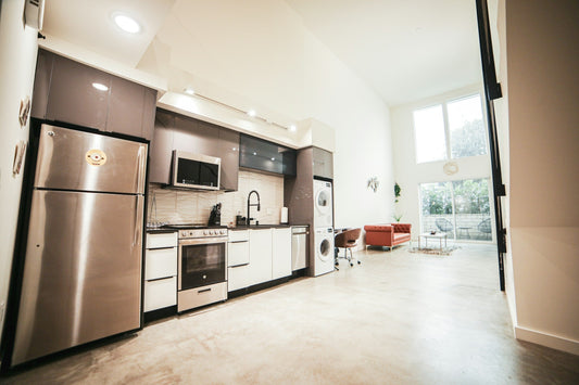 Modern open-concept kitchen with stainless steel appliances and stacked washer-dryer unit, ideal for compact living spaces and condo layouts.