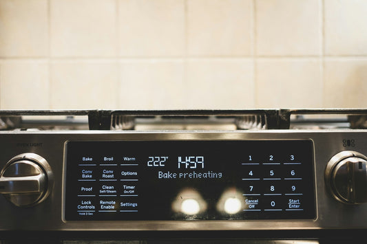 Close-up of a modern electric oven control panel with digital display showing preheat mode, ideal for showcasing smart cooking appliance features in Canada.