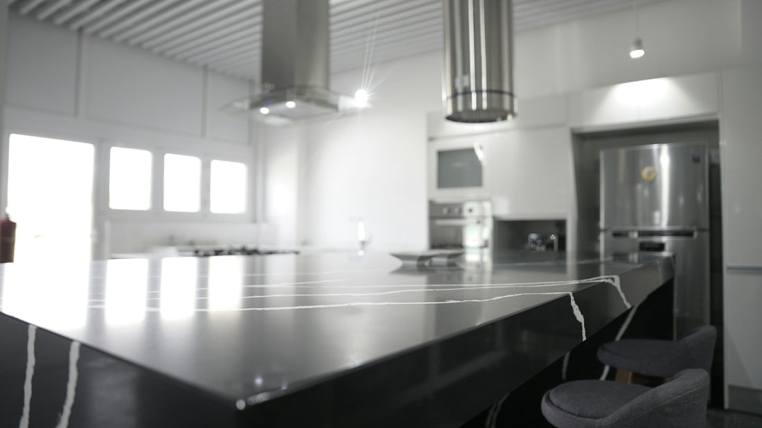 Modern kitchen with stainless steel appliances, including a French door fridge and built-in oven, featuring a sleek black quartz island countertop with bar seating. Ideal for showcasing new appliances in a contemporary Canadian home.