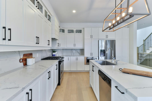 Modern kitchen with stainless steel appliances including a dishwasher, fridge, gas range, and microwave, set against white cabinetry and marble countertops. Perfect example of a kitchen appliance package in a Canadian home.