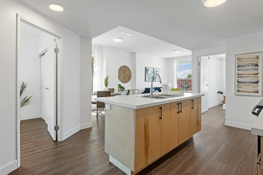 Modern condo kitchen with a central island and stainless steel sink, surrounded by white walls, wooden floors, and natural light, ideal for small space living in Canada.